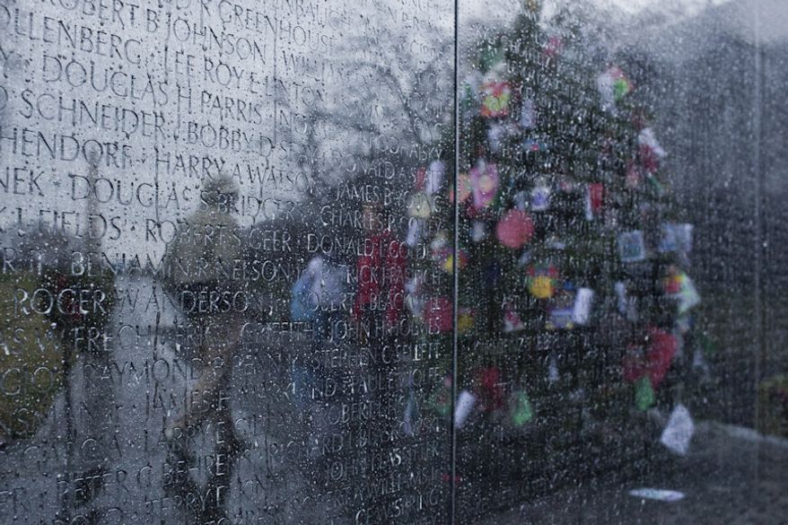 Visitors are seen reflected in the rain streaked Vietnam Memorial wall by the Christmas tree in the Vietnam Memorial in Washington, D.C. on Dec. 21, 2011. (T.J. Kirkpatrick/ The Washington Times)