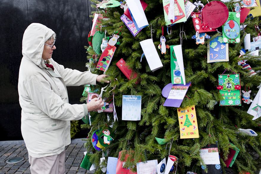 Shirley Salchert of Vancouver, British Columbia, replaces an ornament that fell off of the Christmas tree at the Vietnam Veterans Memorial in Washington on Wednesday, Dec. 21, 2011. "It's a moving place to be," said Ms. Salchert, on a visit with her son, who works for the North American Aerospace Defense Command. (T.J. Kirkpatrick/The Washington Times)