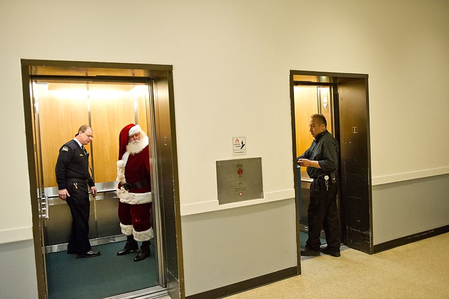 Michael Graham, who plays Santa, is escorted to his chair to begin his morning shift at Tysons Corner Center in Tysons Corner on Wednesday, Dec. 14, 2011. This is Mr. Graham's 22nd year as the Santa at the shopping center, where, from Thanksgiving to Christmas Eve, he can be seen greeting children and some young adults. (Andrew Harnik/The Washington Times)