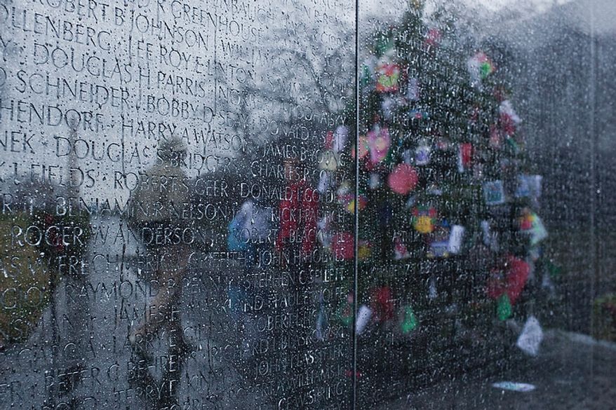 Visitors are reflected next to a Christmas tree on the rain-streaked Vietnam Veterans Memorial wall in Washington on Wednesday, Dec. 21, 2011. (T.J. Kirkpatrick/The Washington Times)