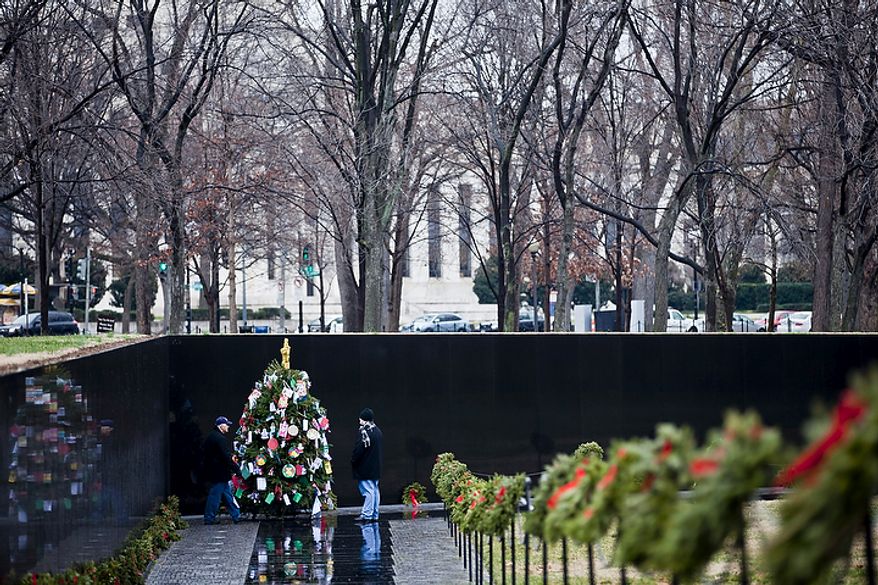 David Ingram (left) of Jacksonville, Fla., and his son Ty look at the Christmas tree in the Vietnam Veterans Memorial in Washington on Wednesday, Dec. 21, 2011. Mr. Ingram, a retired U.S. Army Reserve member, said, "This is my generation ... it just amazes me how many people died." (T.J. Kirkpatrick/The Washington Times)
