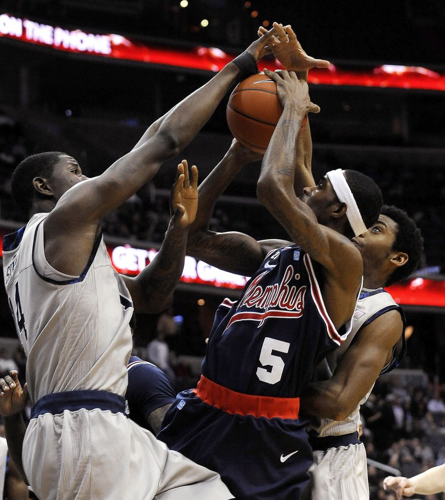 Memphis guard Will Barton (5) has his shot blocked by two Georgetown defenders, Henry Sims, left, and Hollis Thompson, right, during first half, Thursday, Dec. 22, 2011, in Washington. Georgetown defeated Memphis 70-59. (AP Photo/Richard Lipski)