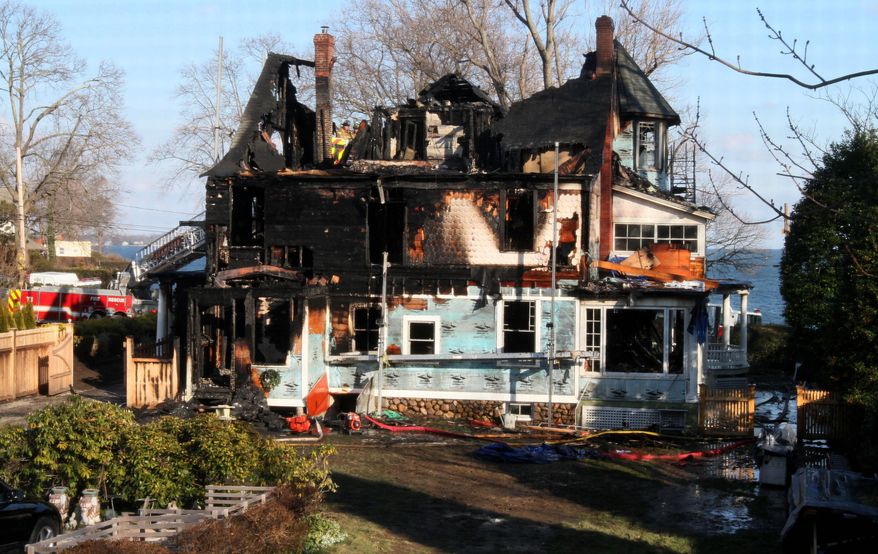 Firefighters investigate a house where an early morning fire left five people dead Sunday, Dec. 25, 2011, in Stamford, Conn. Officials said the fire, which was reported shortly before 5 a.m., killed two adults and three children. Two others escaped. (AP Photo/Tina Fineberg)