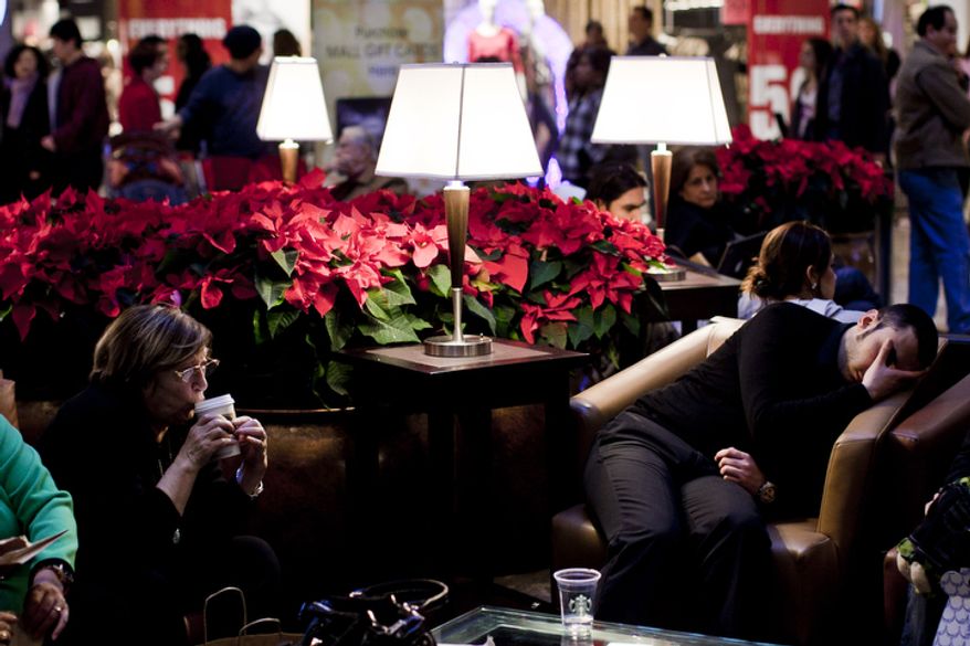 Widad Parsons, of Ashburn, Va., left, sips coffee while taking a break as a weary shopper naps nearby at the Tysons Corner Center mall in McLean, Va., on Dec. 26, 2011. The National Retail Federation projected this years' holiday sales to be up 3 percent over last year, but the Tysons mall is up 4 percent over last year's sales figures for the Black Friday to Christmas Eve period. (T.J. Kirkpatrick/ The Washington Times)