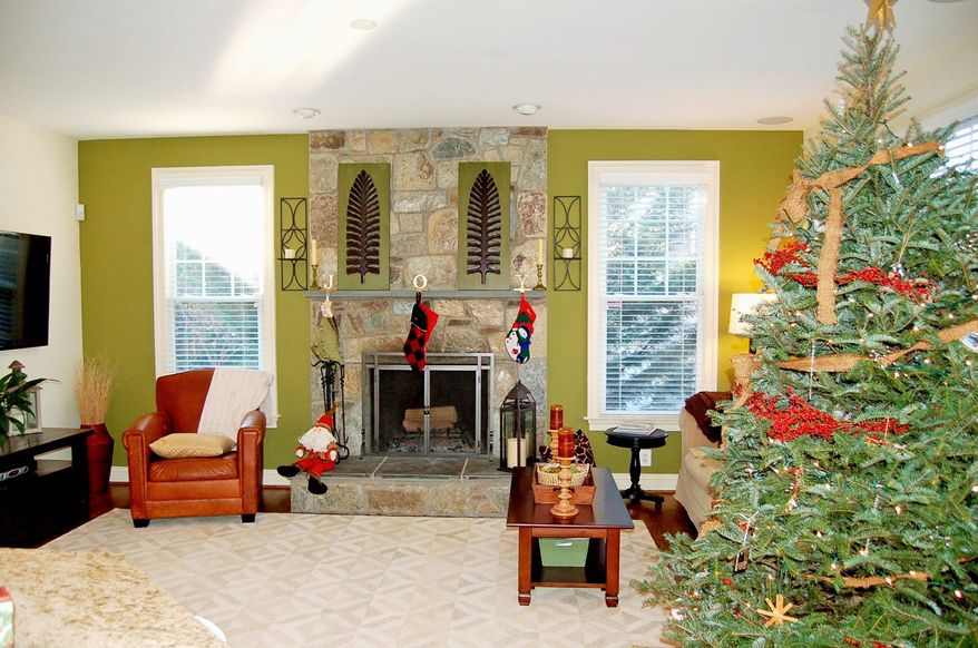 The family room, which is open to the kitchen and breakfast area, features a gas fireplace with a raised hearth and stone surround.