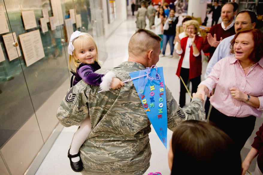 HOME AGAIN: Addison Reel, 2, of Dover, Del., is all smiles in the arms of her father, Air Force Tech Sgt. Scott Reel, upon his arrival at Baltimore-Washington International Thurgood Marshall Airport this month after a four-month deployment to Qatar. Operation Welcome Home Maryland was there to greet him. (Andrew Harnik/The Washington Times)