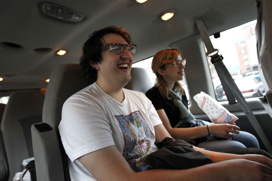Adam Gertner, foreground, and Carly Myers laugh as they watch a movie clip during a movie tour in New Orleans. The tour, launched by New Orleans Movie Tours this summer, takes passengers to locations where famous movie scenes were filmed. The tour also includes peeks at the New Orleans homes of Brad Pitt, Sandra Bullock and John Goodman. (AP Photo/Gerald Herbert)