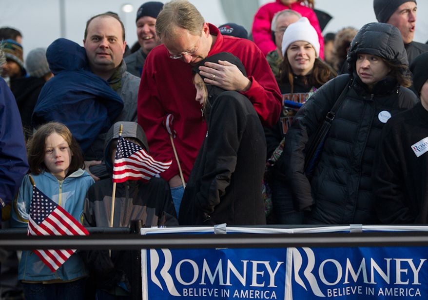 Chris Jenkins of West Des Moines, Iowa, center, comforts his cold 12 year old daughter Lauren while they wait for republican presidential candidate Mitt Romney to arrive for a cold, rainy, early morning rally at a Hy-Vee grocery store, West Des Moines, IA, Friday, December 30, 2011. (Andrew Harnik / The Washington Times)