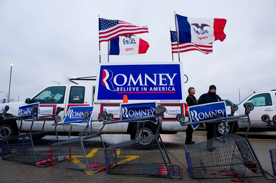 Campaign posters for Republican presidential candidate Mitt Romney can be seen in the parking lot where a cold, rainy, early morning rally is held at a Hy-Vee grocery store, West Des Moines, IA, Friday, December 30, 2011. (Andrew Harnik / The Washington Times)