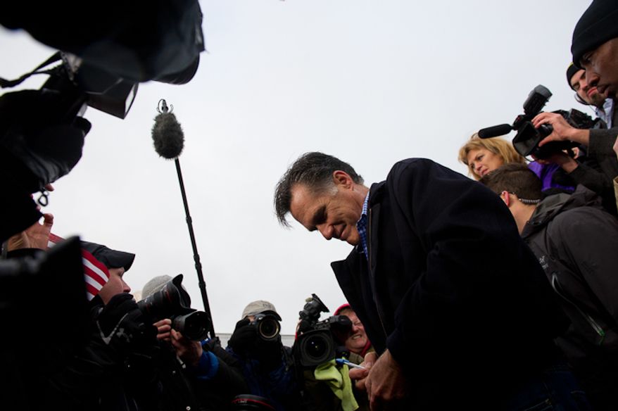 Republican presidential candidate Mitt Romney signs autographs after speaking at a cold, rainy, early morning rally at a Hy-Vee grocery store, West Des Moines, IA, Friday, December 30, 2011. (Andrew Harnik / The Washington Times)