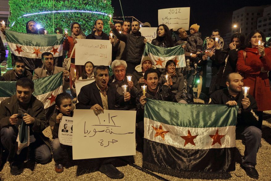 Lebanese and Syrian activists hold Syrian revolutionary flags on Saturday, Dec. 31, 2011, during a candlelight vigil in downtown Beirut in mourning Syrians killed since the uprising against President Bashar Assad's regime began in March. The banner in Arabic reads, "2012 Syria is free." (Associated Press)
