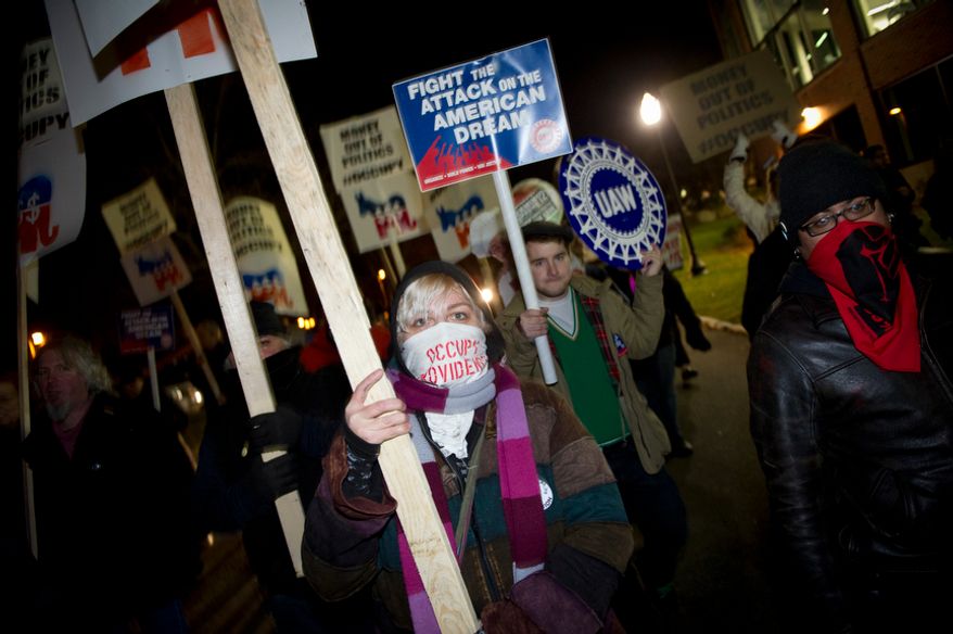 A small group of protesters march along with a brass band on the streets nearby prior to the New Hampshire Republican Presidential Debate at Saint Anselm College in Manchester, N.H., Saturday, January 7, 2012. This debate is the first of two debates this weekend focused on the New Hampshire Republican primary. (Rod Lamkey Jr/ The Washington Times)