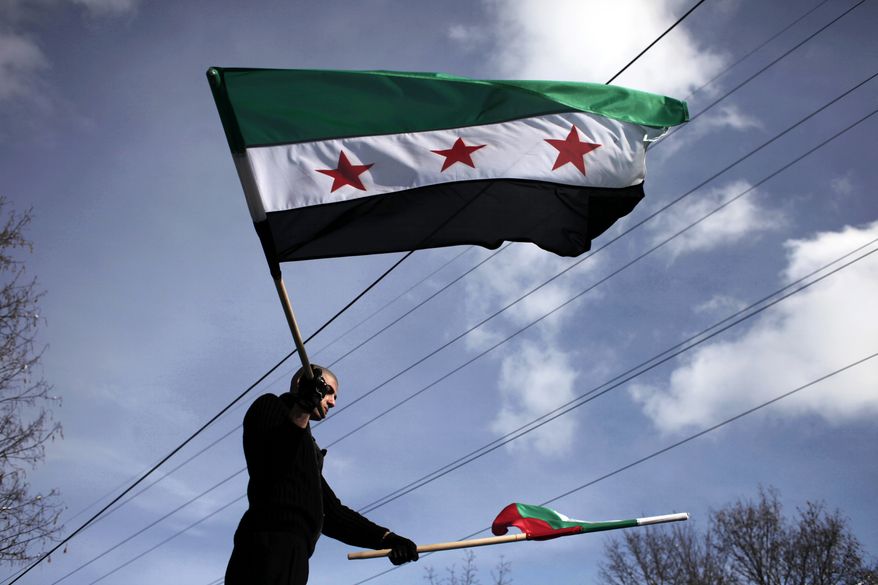 A Syrian immigrant waves Bulgarian and the revolutionary Syrian flag, during a rally against the regime of Syrian President Bashar al-Assad in front of the Syrian embassy in Sofia, on Sunday, Jan. 8, 2012. Syrian opposition groups say the death toll has risen beyond 6,000 and government forces continue to kill protesters despite the presence of Arab League monitors. (AP Photo/Valentina Petrova)