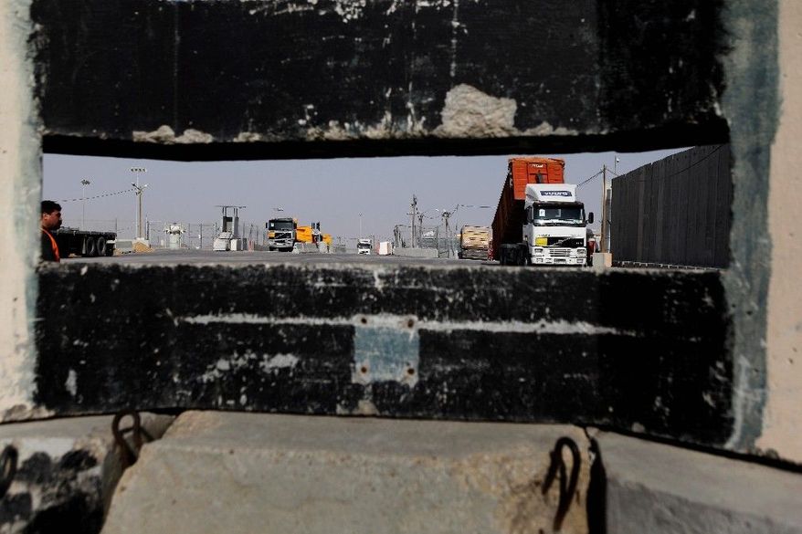 In this Monday, Dec. 19, 2011 photo, seen through a gun slit, trucks with goods destined for Gaza wait to be unloaded on the Israeli side of the Kerem Shalom crossing, between Israel and the Gaza Strip. Each day, dozens of trucks move food, consumer products and industrial materials into the Gaza Strip at this heavily fortified crossing, in an odd arrangement that has turned Israel into a key supplier to a territory governed by its bitter enemy Hamas. (AP Photo/Tsafrir Abayov)