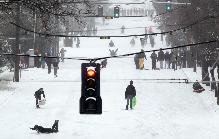 Sledders, skiers, snowboarders and pedestrians take over a snow-covered street in the Queen Anne neighborhood of Seattle on Wednesday, Jan. 18, 2012. (AP Photo/Elaine Thompson)