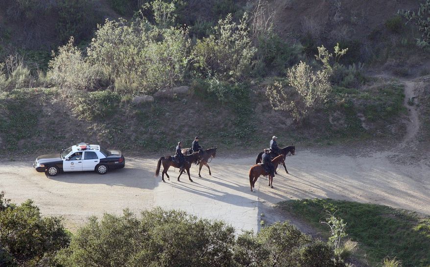 Mounted police officers search the Bronson Canyon area of Griffith Park in Los Angeles on Wednesday, Jan. 18, 2012, after a human head was discovered Tuesday by two people walking their dogs below the famous Hollywood sign. (AP Photo/Jason Redmond)