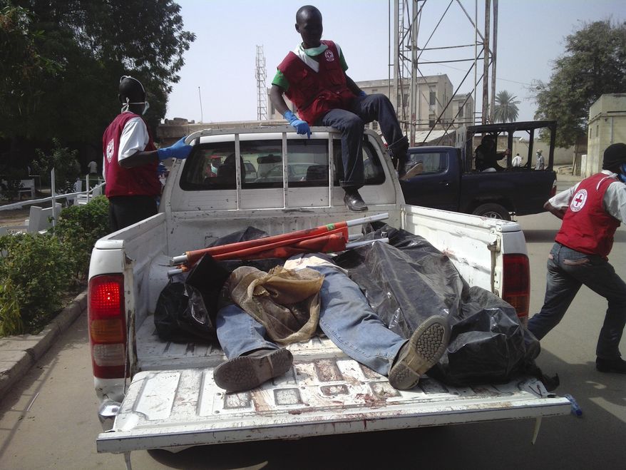Red Cross officials collect bodies from a street in Kano, Nigeria, on Saturday, Jan. 21, 2012, after a bomb blast and gun attacks Friday night. (AP Photo/Salisu Rabiu)