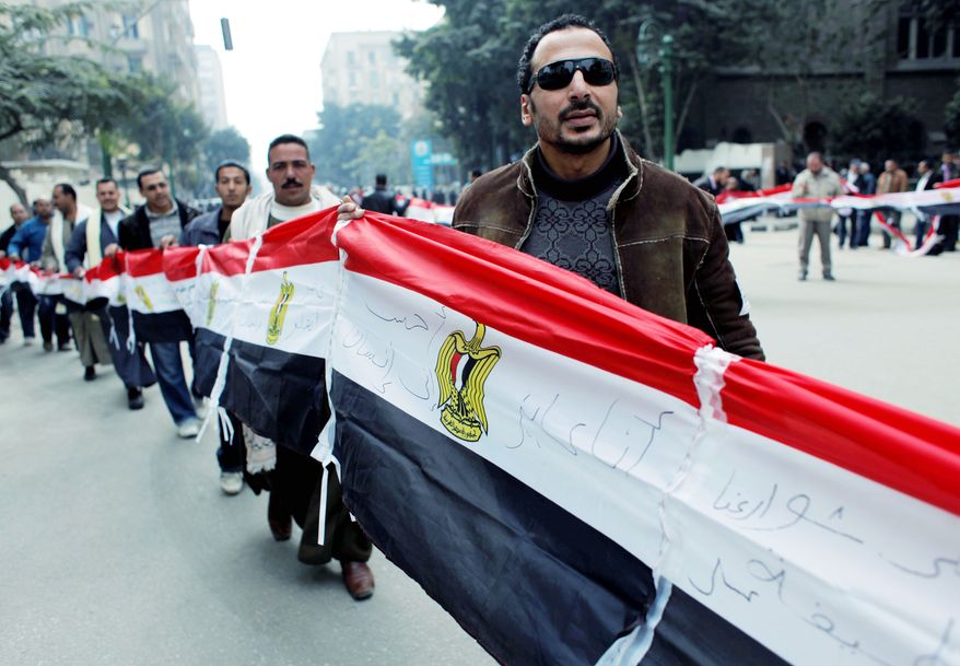 Egyptian protesters carry their national flag outside the People's Assembly building in Cairo during the assembly's opening session Monday. The newly elected assembly, which is made up overwhelmingly of Islamists, will elect a panel to draft a new constitution. Elections for the chamber were the first since Hosni Mubarak's ouster. (Associated Press)