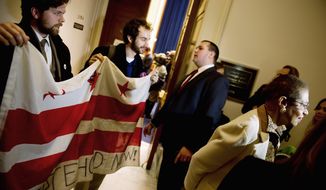 Occupy D.C. protesters Drew Veysey and Sam Jewler (from left) hold a D.C.  flag behind Delegate Eleanor Holmes Norton as she speaks to reporters following a hearing Tuesday about the occupation of McPherson Square. 