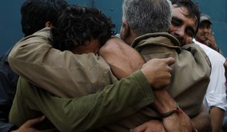 Family members mourn the deaths of three men in Karachi, Pakistan, on Wednesday. Three lawyers were gunned down and one was injured in an ambush by unidentified gunmen riding on a motorcycle, police said. The dead included a father, son and nephew. The motive is not yet known. (Associated Press)