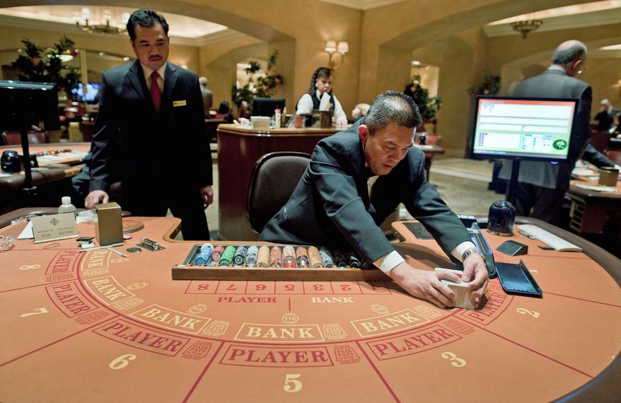 Baccarat dealer Ramiro Nepomuceno (right) shuffles cards as floor supervisor Sam Insyxiengmay looks on while preparing a table for play at the MGM Hotel and Casino on Wednesday in Las Vegas. Baccarat, popular with Asian high rollers, is the most profitable table game for casinos. (Associated Press)