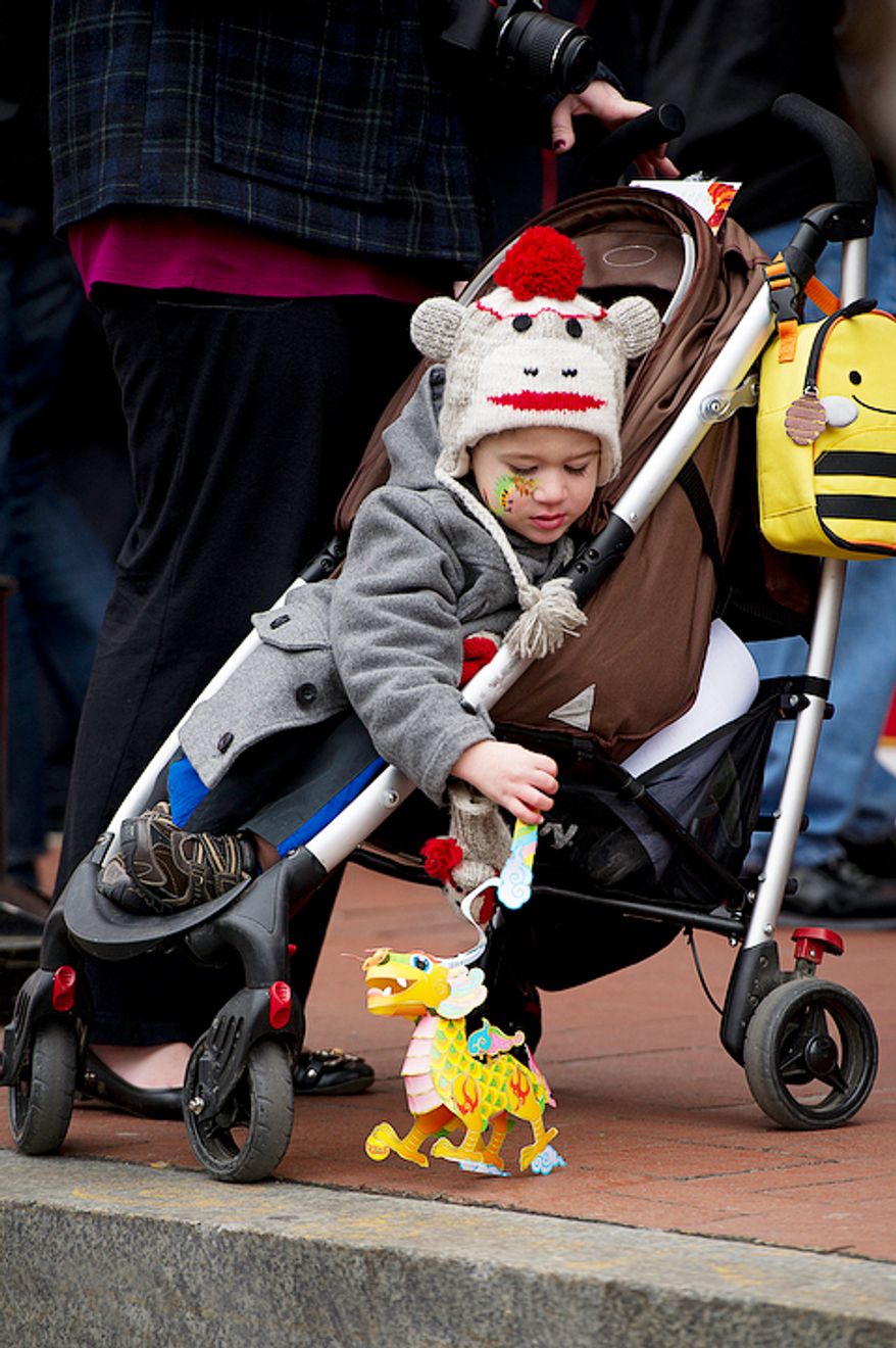 Riley Easter, 3, of Highland, Md. plays with his paper dragon lantern along H Street N.W. in Washington, D.C. as he waits for the beginning of the Chinese New Year Parade. The Chinese Cultural Center sold the paper dragons to raise funds for its programming. (Barbara L. Salisbury/The Washington Times)
