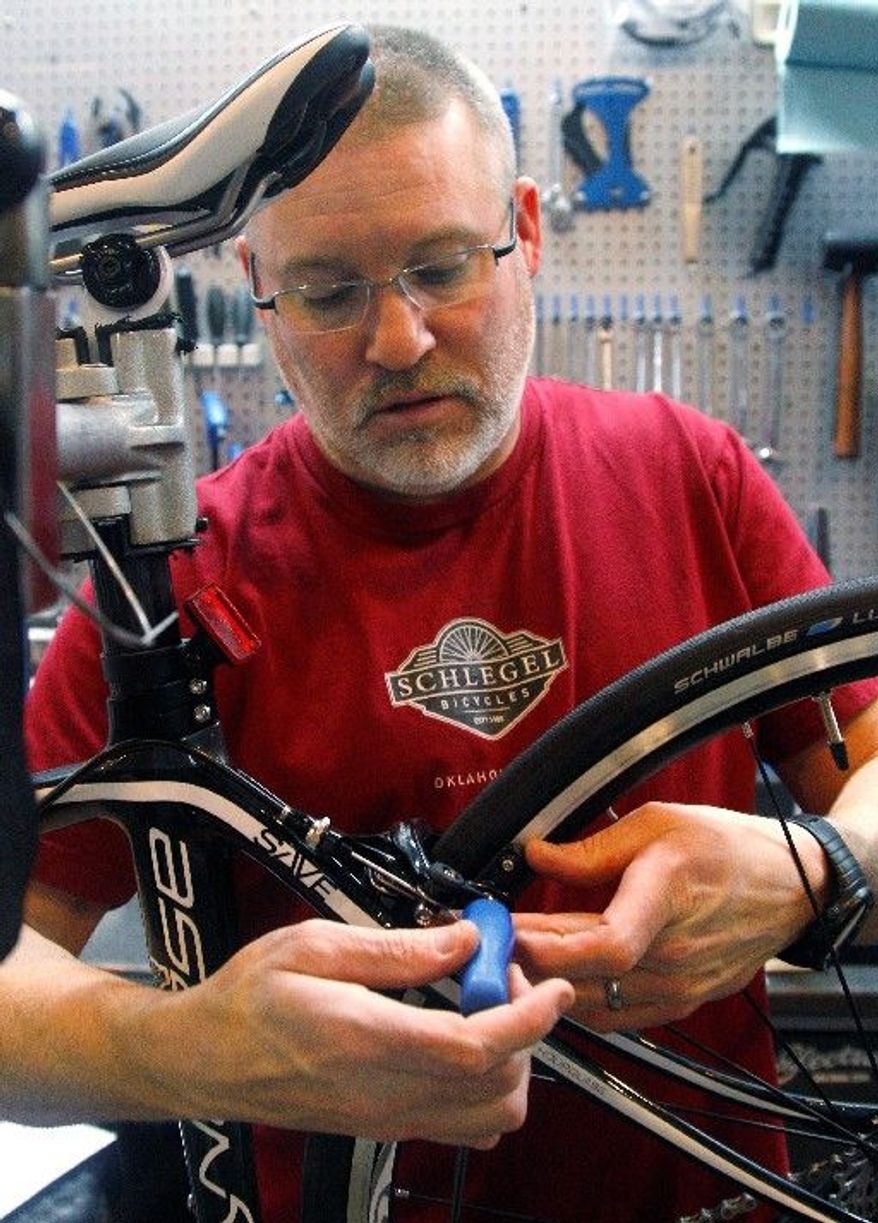 Steve Schlegel, owner of Schlegel Bicycles, works on a bicycle in the shop's pro shop in Oklahoma City on Thursday. In Oklahoma, Republican Gov. Mary Fallin says gradually cutting the top income-tax rate of 5.25 percent will make the state more attractive to businesses, help spur economic growth and ensure Oklahoma is competitive against neighboring states such as Texas. (Associated Press)