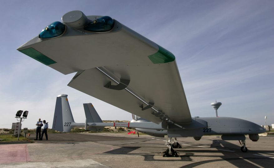 **FILE** Israeli Air Force officers stand March 7, 2007, next to an Israeli army Heron TP drone, also known locally as the Eitan, during a display at the Palmahim Air Force Base. (Associated Press)