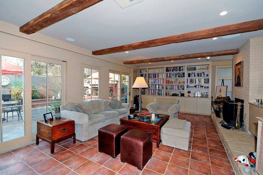 The family room, part of an addition built about 10 years ago, features beamed ceilings, tile floors, and built-in bookcases and cabinets. A wall of floor-to-ceiling windows and French doors overlook the terrace.
