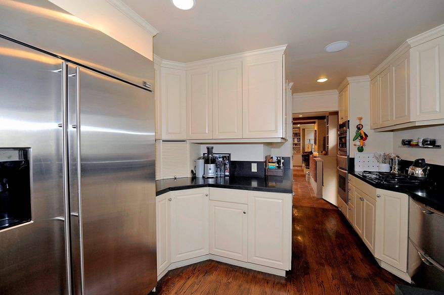 The home's original hardwood floors extend into the kitchen, which has been updated with recessed lighting, stainless steel appliances, black granite counters and white cabinetry.