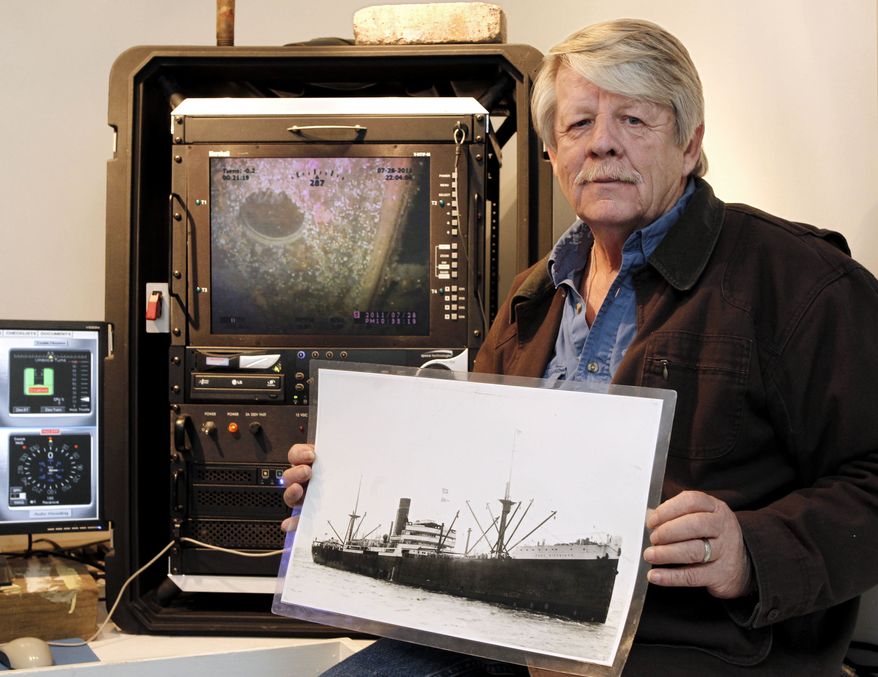 Greg Brooks, co-manager of Sub Sea Research, is seen aboard the salvage ship Sea Hunter in Boston Harbor Wednesday, Feb. 1, 2012, holding a picture of the British merchant ship Port Nicholson, which was sunk by a German U-boat in 1942 with a cargo of 71 tons of platinum now worth about $3 billion. (AP Photo/Winslow Townson)