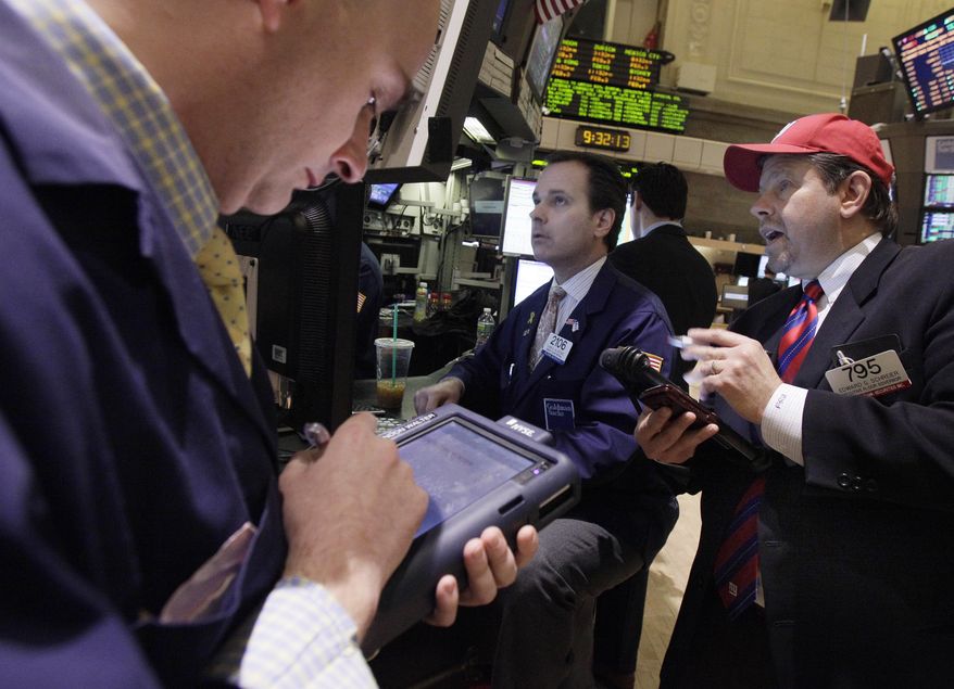 Trader Edward Schreier (right) works Feb. 3, 2012, with specialist John Alatzas (center) on the floor of the New York Stock Exchange. (Associated Press)