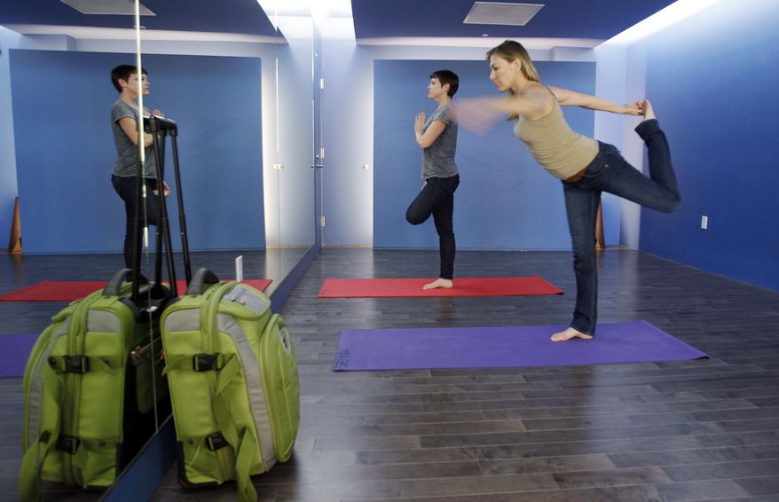 In this Friday, Jan. 27, 2012, photo, travelers Maria Poole, right, and Lindsey Shepard, practice yoga at San Francisco International Airport's new Yoga Room. The quiet, dimly lit studio officially opened last week in a former storage room just past the security checkpoint at SFO's Terminal 2. (AP Photo/Paul Sakuma)