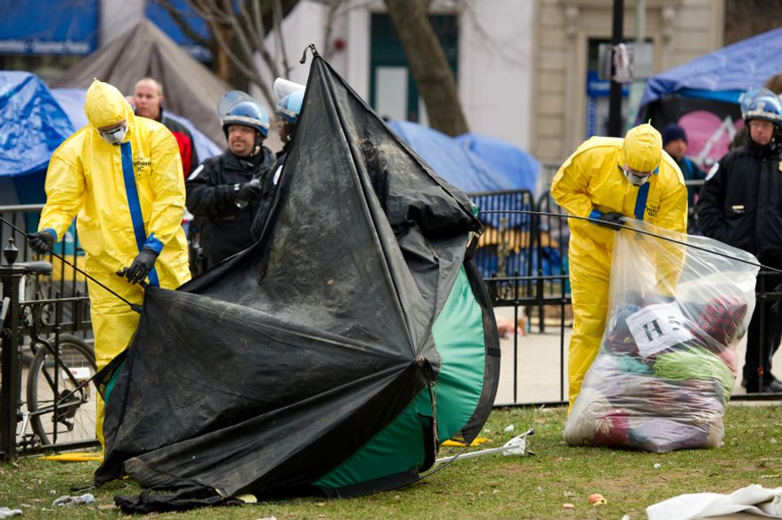 Park officials in hazmat suits break down tents and camping equipment during an early morning, peaceful raid on the Occupy encampment at McPherson Square, Washington, D.C., Saturday, Feb. 4, 2012. (Andrew Harnik/The Washington Times)