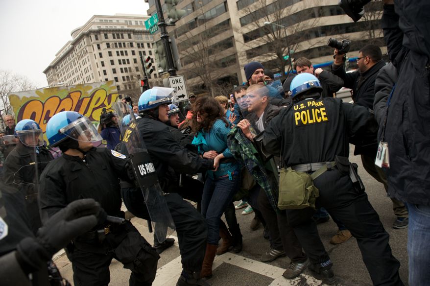 A raid on the Occupy encampment at McPherson Square in Washington, D.C., turns ugly as Park Police officers try to clear protesters from sections of the park, Saturday, Feb. 4, 2012. Tents and camping equipment were removed by park police and maintenance officials, some dressed in hazmat suits. (Andrew Harnik/The Washington Times)