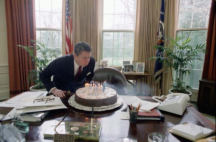 President Reagan blows out the candles on his birthday cake in the Oval Office in 1982, the day he turned 71. Events are planned for Monday across the country marking what would have been his 101st birthday, including a 21-gun salute. (Photo courtesy of the Ronald Reagan Presidential Library)