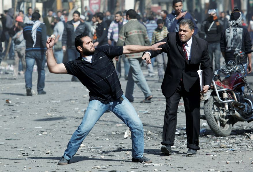 A man urges a protester to stop throwing stones toward security forces during clashes near the Egyptian Interior Ministry in Cairo on Sunday, the fourth day of violence involving youths protesting a deadly soccer riot. (Associated Press)