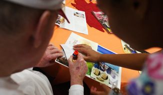 **FILE** Monica Leon Galarza (right), a nursing assistant, helps Archie, a resident, make a collage on Oct. 15, 2009, during an art program at the Alzheimer&#39;s disease unit of the Patriots Colony retirement community in Williamsburg, Va. (Associated Press/The Daily Press)