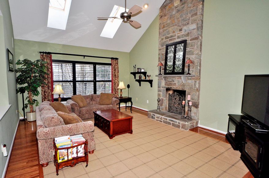 The two-story family room has a floor-to-ceiling stone wood-burning fireplace and two skylights. A triple window overlooks the backyard.