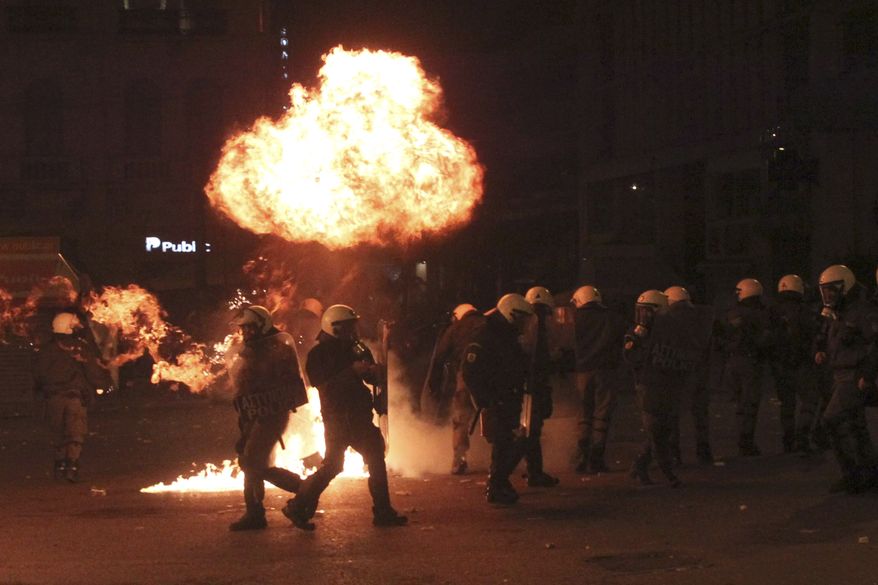 A petrol bomb explodes over riot police during clashes in Athens, Sunday, Feb. 12, 2012. Riots engulfed central Athens and at least 10 buildings went up in flames in mass protests late Sunday as lawmakers prepared for a historic parliamentary vote on harsh austerity measures demanded to keep the country solvent and within the eurozone. (AP Photo/Petros Giannakouris)