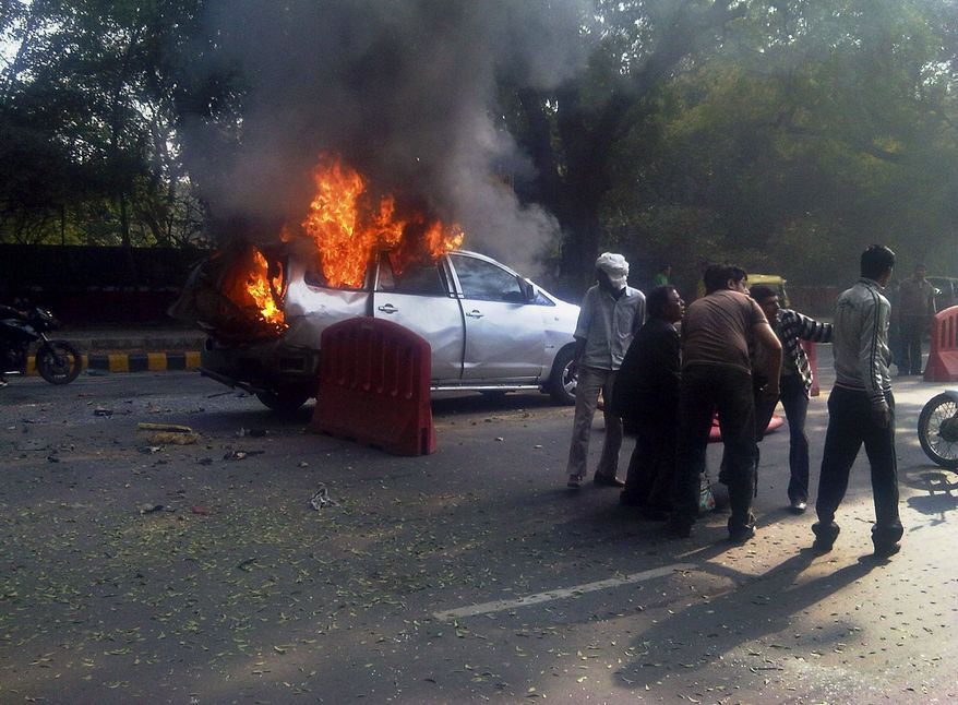 An injured person is carried Feb. 13, 2012, from a burning car belonging to the Israeli Embassy following an explosion in New Delhi. The wife of an Israeli diplomat was injured in the explosion, the same day an Israeli Embassy staffer in Georgia found a bomb underneath his car, which was dismantled before exploding, according to Indian and Israeli media reports. (Associated Press/Economic Times)