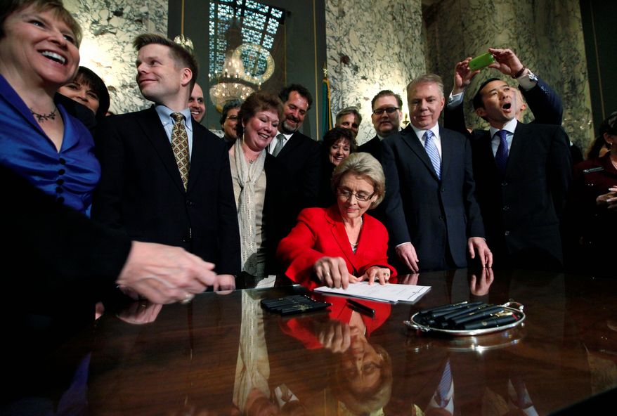 Washington state Gov. Chris Gregoire is surrounded by legislators and others Monday as she signs into law a bill legalizing same-sex marriage. The law is to take effect June 7, but opponents are mounting a repeal effort. (Associated Press)