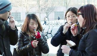 **FILE** Students try samples of AeroShot, an inhalable caffeine, from a lipstick-sized canister on the campus of Northeastern University in Boston. The FDA will review the safety and legality of the advertised dietary supplement. (Associated Press)