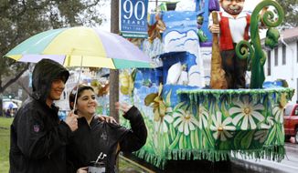 Carnival revelers wave to passing floats near the start of the Krewe of Endymion parade, which was postponed for an hour because of heavy rain, in New Orleans on Saturday, Feb. 18, 2012. (AP Photo/Jonathan Bachman)