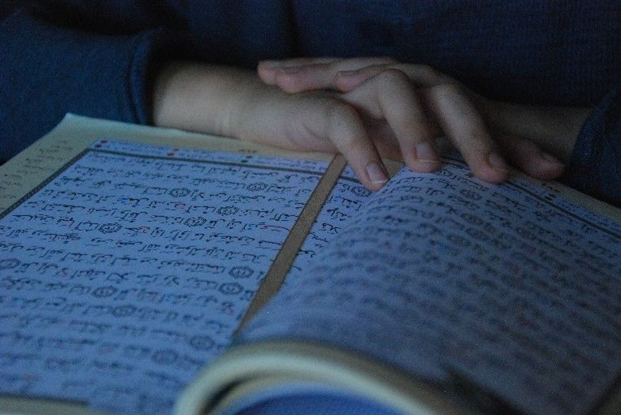 Ahmad Bannout, 12, reads from the Koran at his home. His mother says her children read for memorization after practicing in their Arabic workbooks. (Jessica Carpenter/The Washington Times)