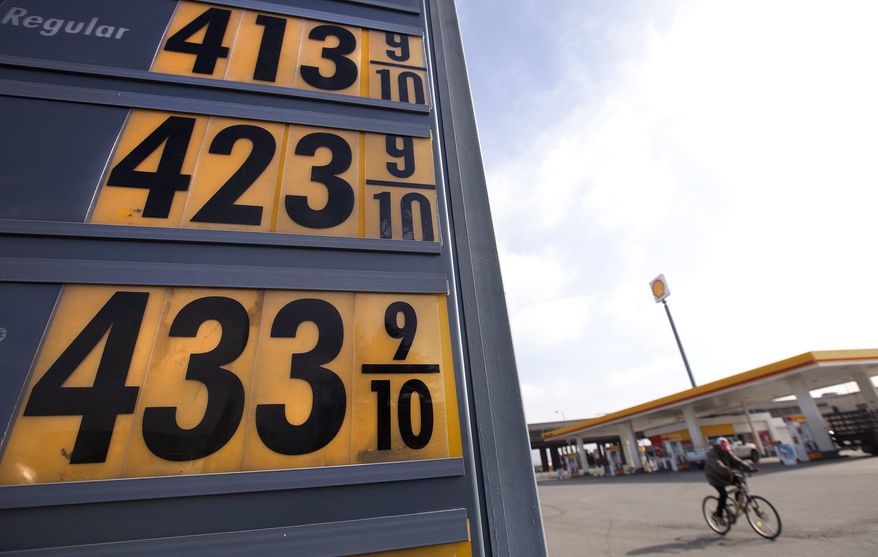 **FILE** Gasoline prices are displayed Feb. 21, 2012, as a man rides his bicycle past them at a station in Oakland, Calif. (Associated Press)