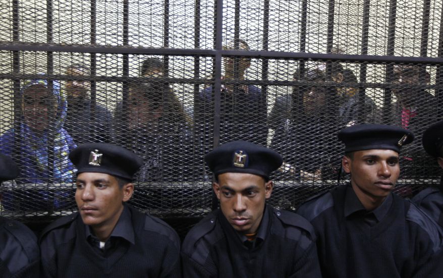 Policemen in a Cairo courtroom on Sunday, Feb. 26, 2012, sit in front of Egyptian employees of several pro-democracy groups charged with using foreign funds to foment unrest. The trial of 16 Americans and 27 others has plunged relations with the U.S. into the deepest crisis in decades. (AP Photo/Khalil Hamra)