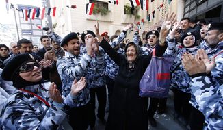 A Syrian woman (center) dances between pro-Syrian-regime supporters wearing police uniforms as they celebrate outside a polling station during a referendum on the new constitution in Damascus, Syria, on Sunday, Feb. 26, 2012. (AP Photo/Muzaffar Salman)