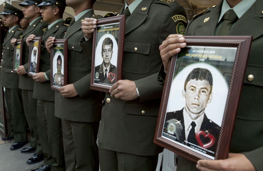 Police officers in Bogota, Columbia, on Thursday Feb. 23, 2012, hold photographs of fellow officers who were kidnapped by rebels of the Revolutionary Armed Forces of Colombia (FARC). (AP Photo/Fernando Vergara)