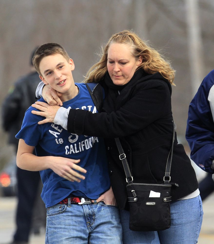 Doug Gasper, a ninth-grader at Chardon High School, is hugged Feb. 27, 2012, by his mother, Sandy, as they leave Maple Elementary School in Chardon, Ohio. Students assembled at Maple Elementary School after a gunman opened fire inside the high school's cafeteria at the start of the school day, wounding four students, officials said. (Associated Press)
